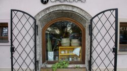 Schaufenster mit offenem Eisentor, Rundbogenfenster mit Körben und Waren, Schild mit der Aufschrift CABRERAS.