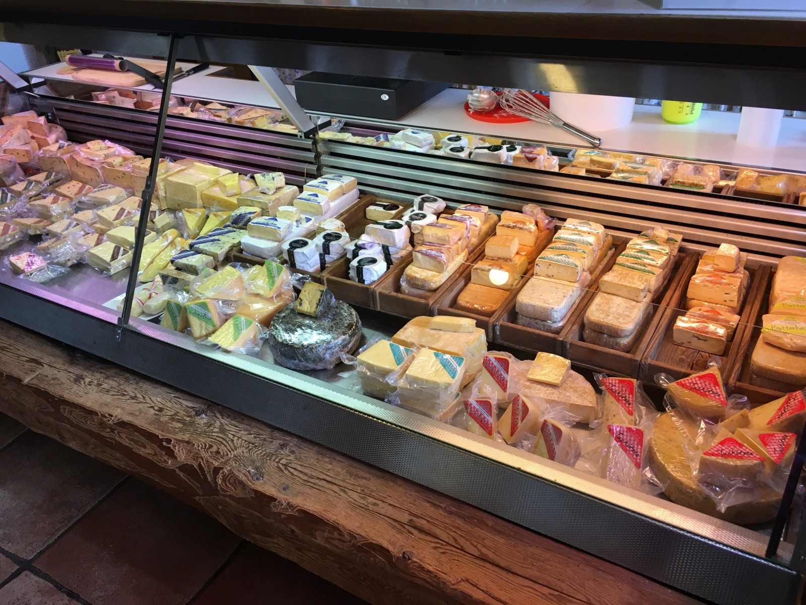 Verschiedene Käsescheiben und -blöcke in einem Kühlregal für Feinkost.