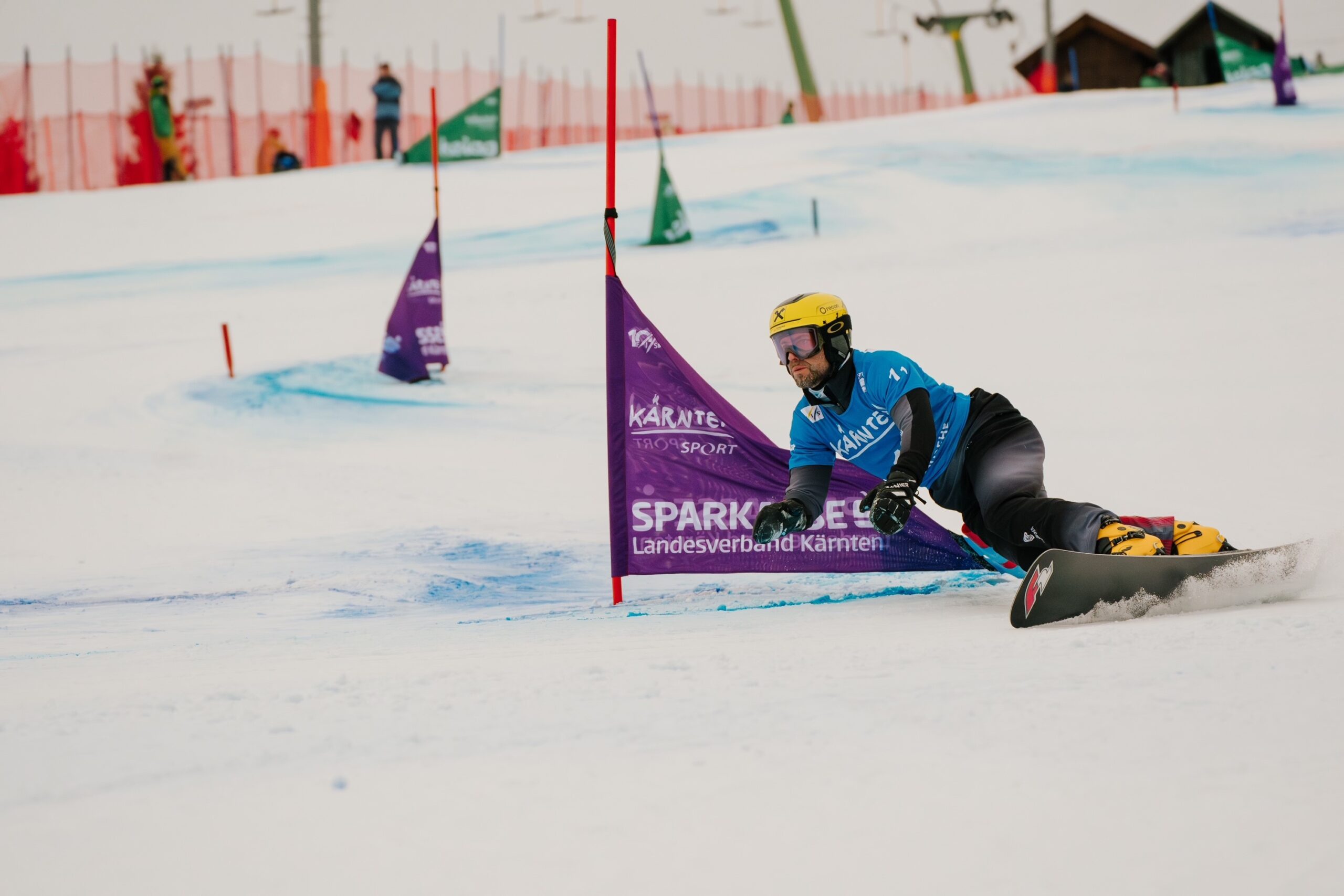 Der Snowboard-Weltmeister Andreas Prommegger aus dem Salzburger Land rast in blauem Trikot und gelbem Helm um ein Slalomtor.