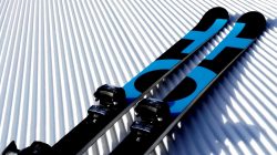 Ein Paar blaue und schwarze Skier liegen auf frisch präpariertem, geriffeltem Schnee.