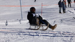 Eine Person rodelt bei den Afrikanischen Rodelmeisterschaften in Sankt Johann im Pongau bergab; Zuschauer schauen zu.