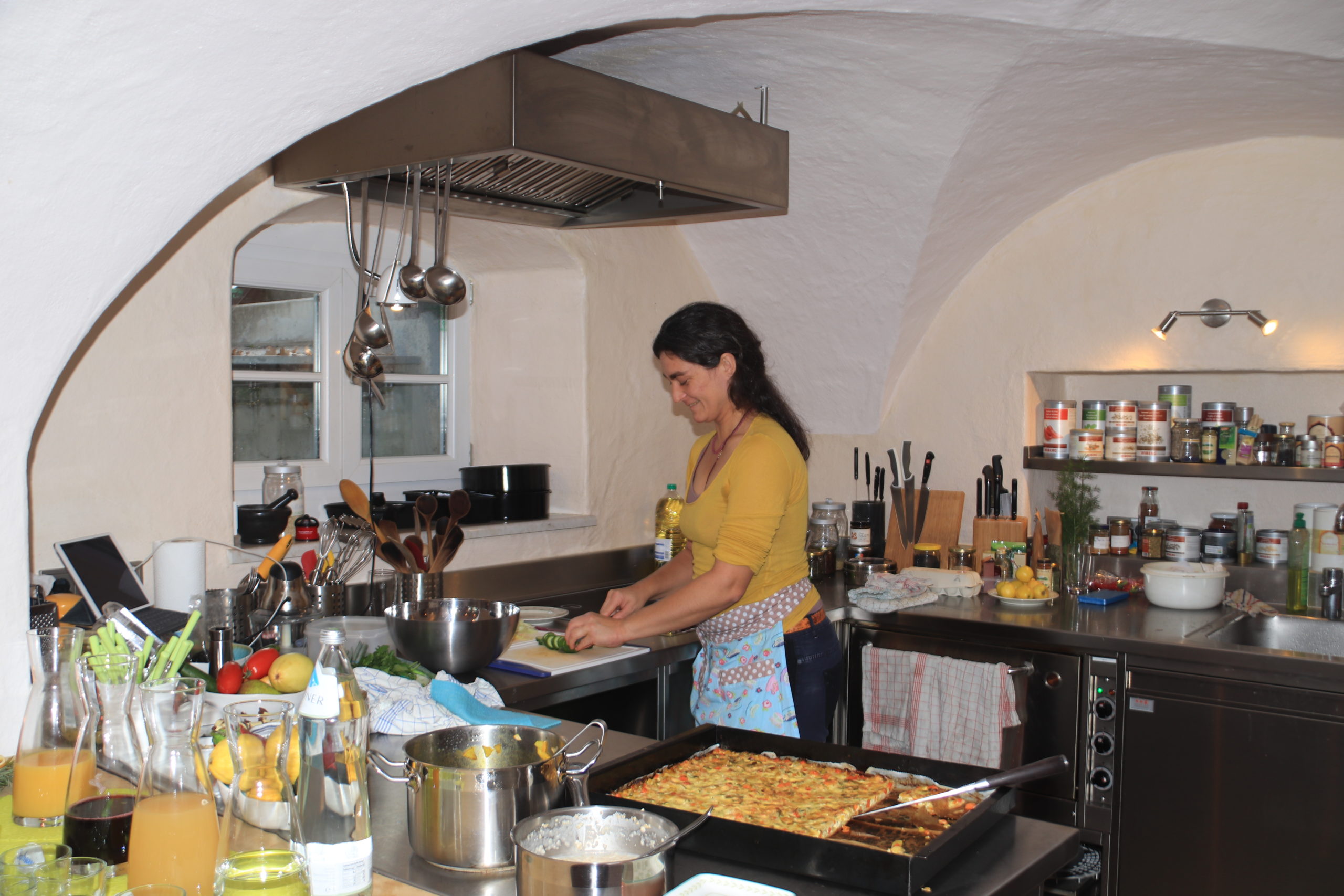 Eine Frau im gelben Hemd bereitet das Essen in der Tauglerei, Zentrum für Ayurveda und vieles mehr, zu.