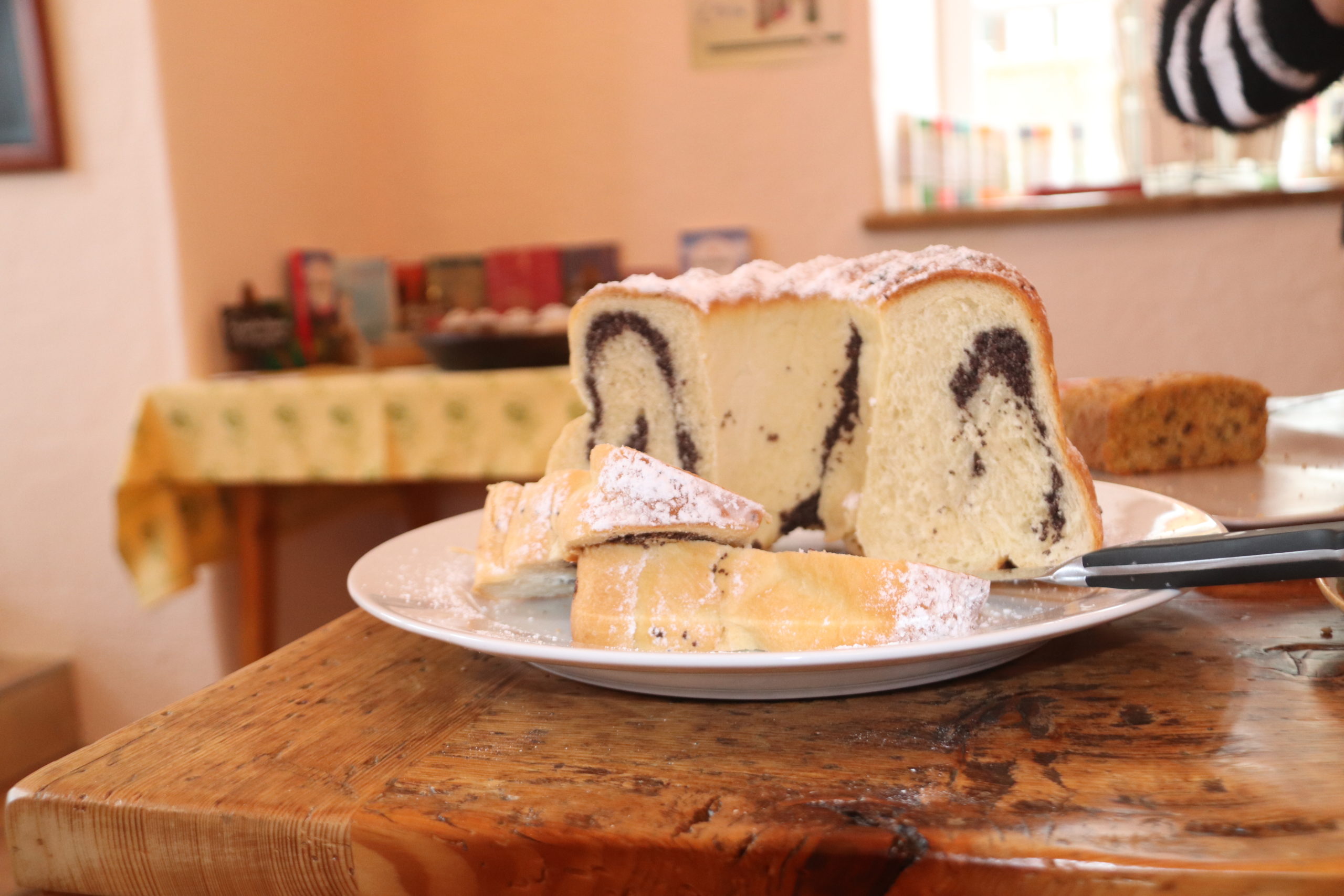 Ein in Scheiben geschnittener Marmorkuchen mit Puderzucker liegt auf einem weißen Teller in der Tauglerei, Zentrum für Ayurveda.