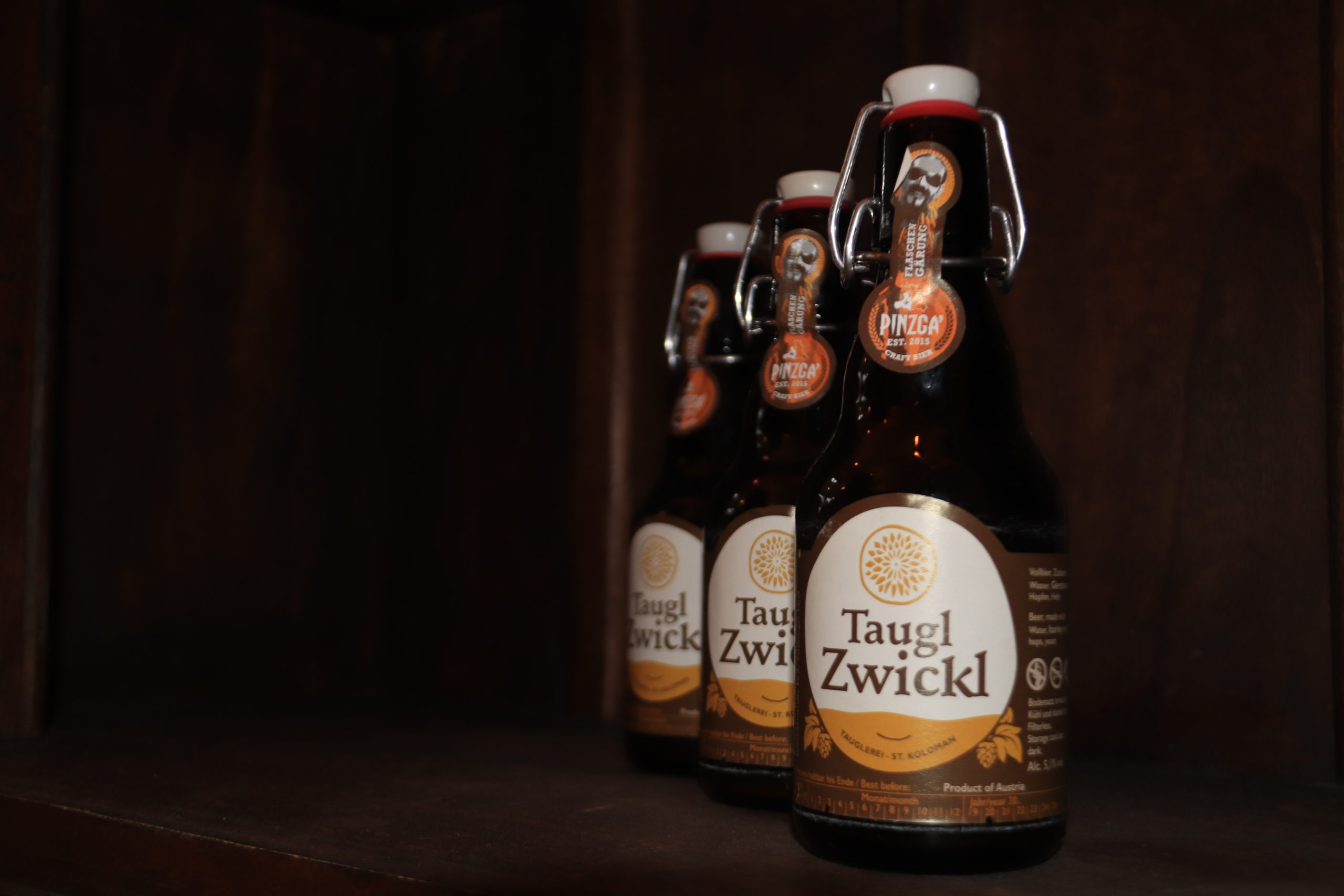 Vier Taug Zwickl Bierflaschen auf einem Holzregal mit der Aufschrift Die Tauglerei, Zentrum für Ayurveda und mehr.