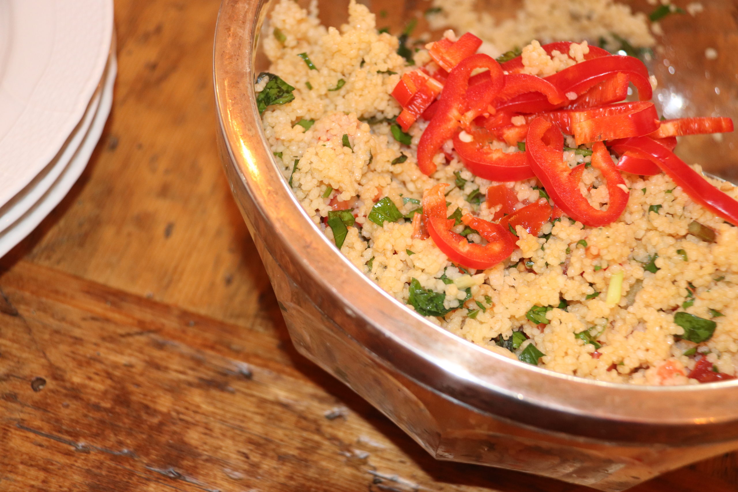 Eine Schüssel Couscous-Salat mit Grünzeug und roter Paprika, genossen in der Tauglerei, Zentrum für Ayurveda und mehr.