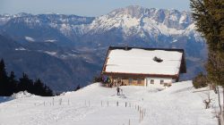 Verschneite Hütte in Bergnähe - die Enzian-Hütte ist ein Tipp für Skitouren-Einsteiger unter klarem Himmel.