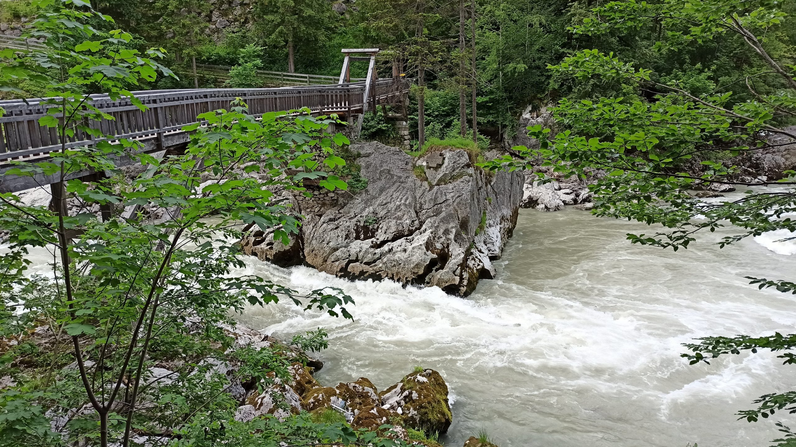 Über wildem Wasser und massivem Felsen überqueren wir die prächtige Holzbrücke