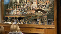 Kinder betrachten eine detaillierte Grundner Krippe mit Miniaturgebäuden und -figuren.