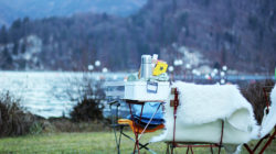 Ein gemütliches Picknick auf der Alm Marie am See mit Stühlen, Tisch, Thermoskanne und einer Felldecke.
