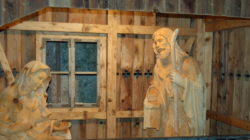 Holzkrippe an einem Fenster, Teil des Kripperlweg-Advent in Lofer, in einer rustikalen Holzkonstruktion.