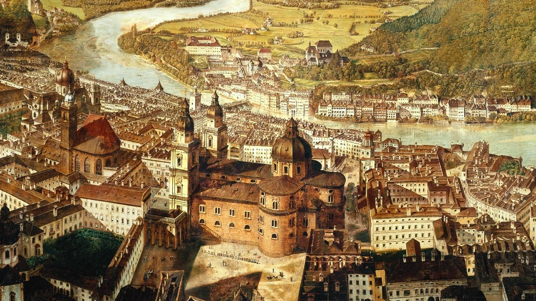 Luftaufnahme einer historischen europ&auml;ischen Stadt mit gro&szlig;en Kirchen, einem Fluss und umliegenden gr&uuml;nen H&uuml;geln.
