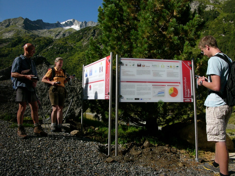 Wanderer informieren sich bei einer Schautafel entlang des Energielehrpfades bei der Postalm © Wildkogel-Arena Neukirchen & Bramberg