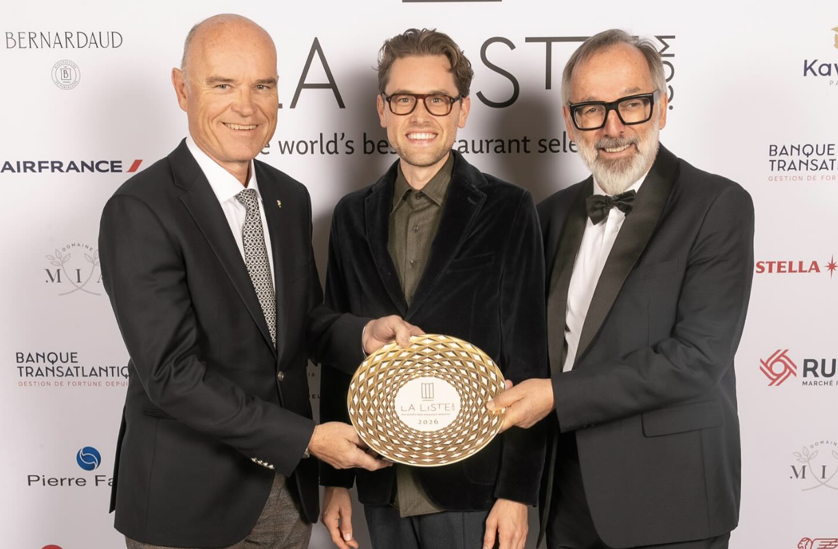 Drei Männer in Anzügen, die lächelnd eine La Liste 2024-Plakette vor einem Markenhintergrund halten.