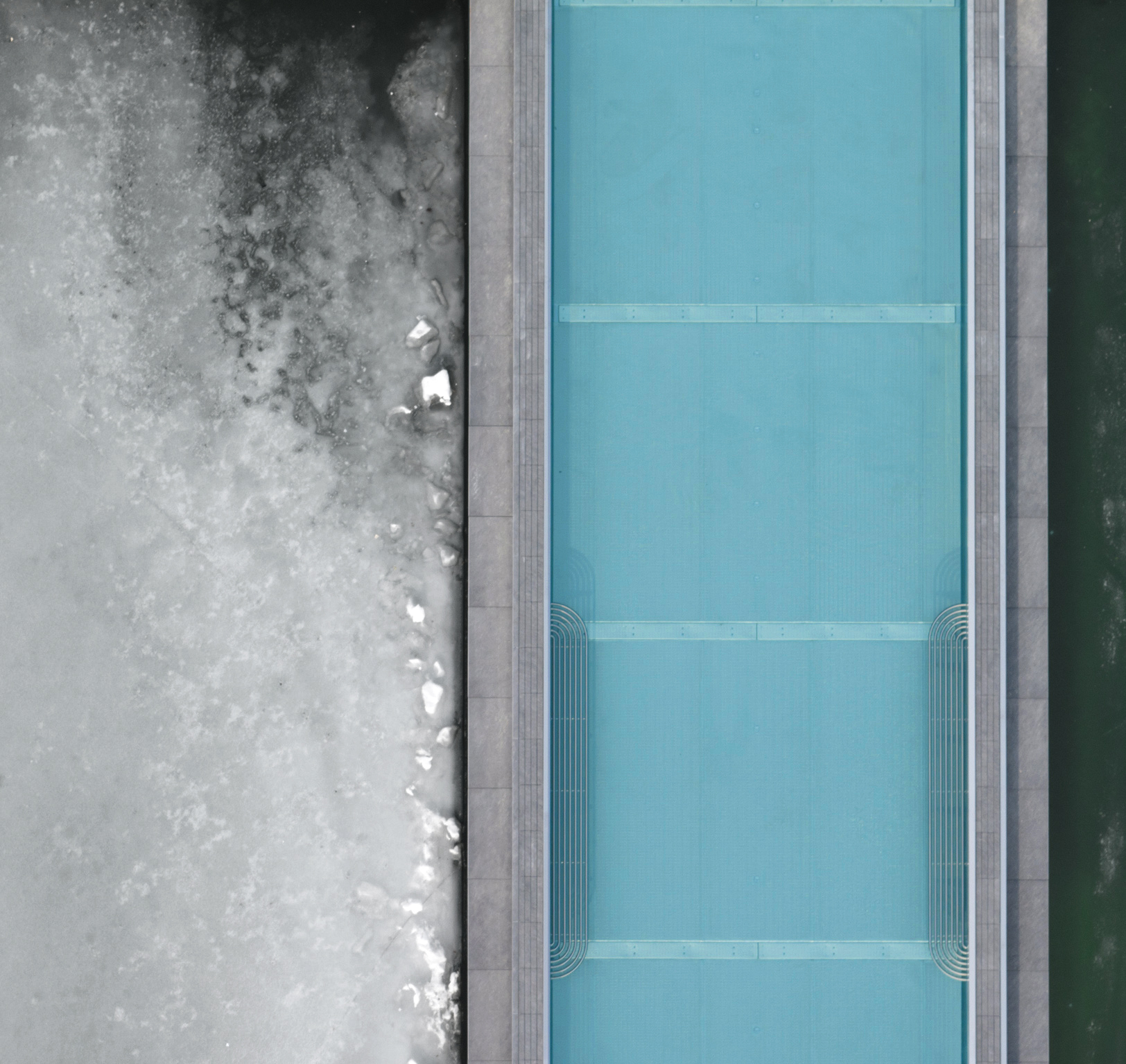 Luftaufnahme eines rechteckigen blauen Pools mit gefrorener, eisiger Oberfläche und dunklem Wasser.