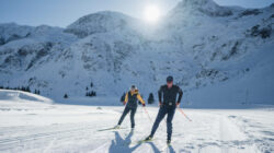 Zwei Personen beim Skilanglauf auf einer verschneiten Loipe, die an die alpinen Abenteuer von Bernhard Gruber erinnert.