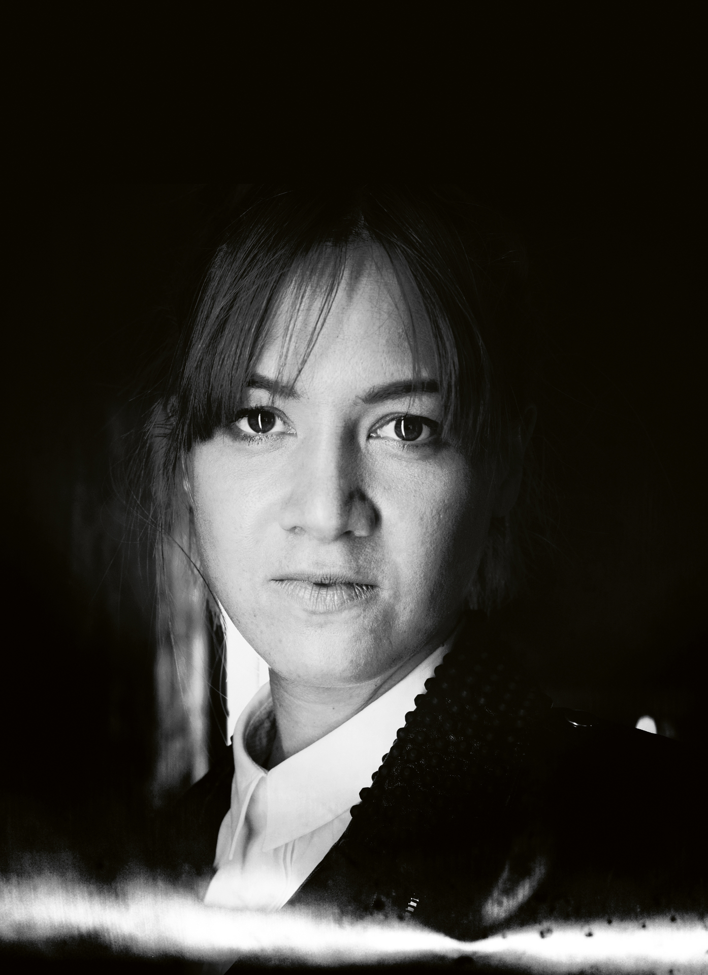 Schwarz-wei&szlig;es Portr&auml;t einer Frau mit Pony, die ein Hemd mit Kragen tr&auml;gt und direkt in die Kamera schaut.