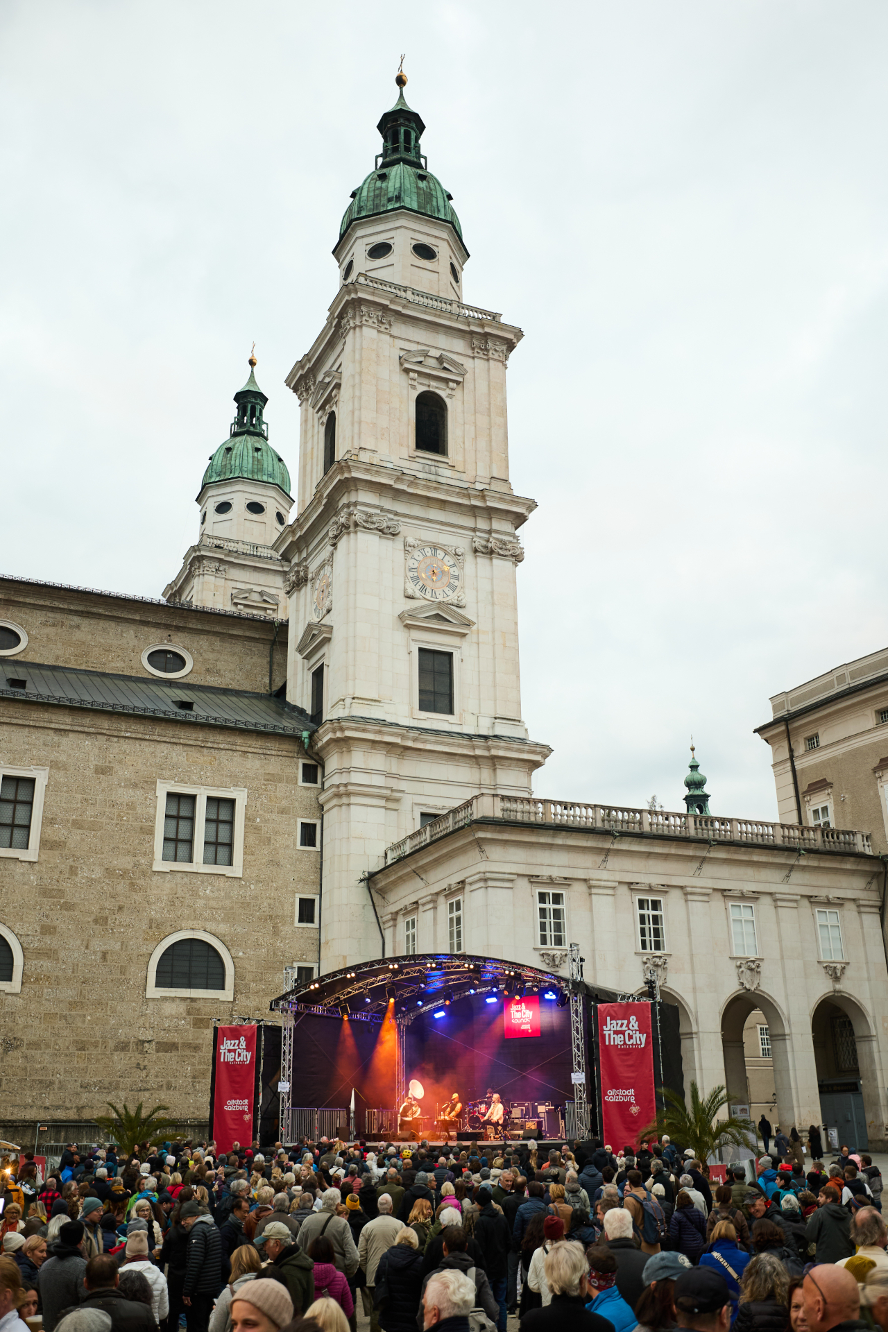 Eine Menschenmenge verfolgt ein Live-Konzert unter freiem Himmel vor einer großen historischen Kirche mit zwei Türmen.