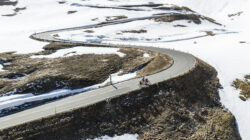 Mit dem E-Bike und den Skitourenskiern auf die Gipfel der Hohen Tauern radelt ein Sportler durch Schnee und Gras.