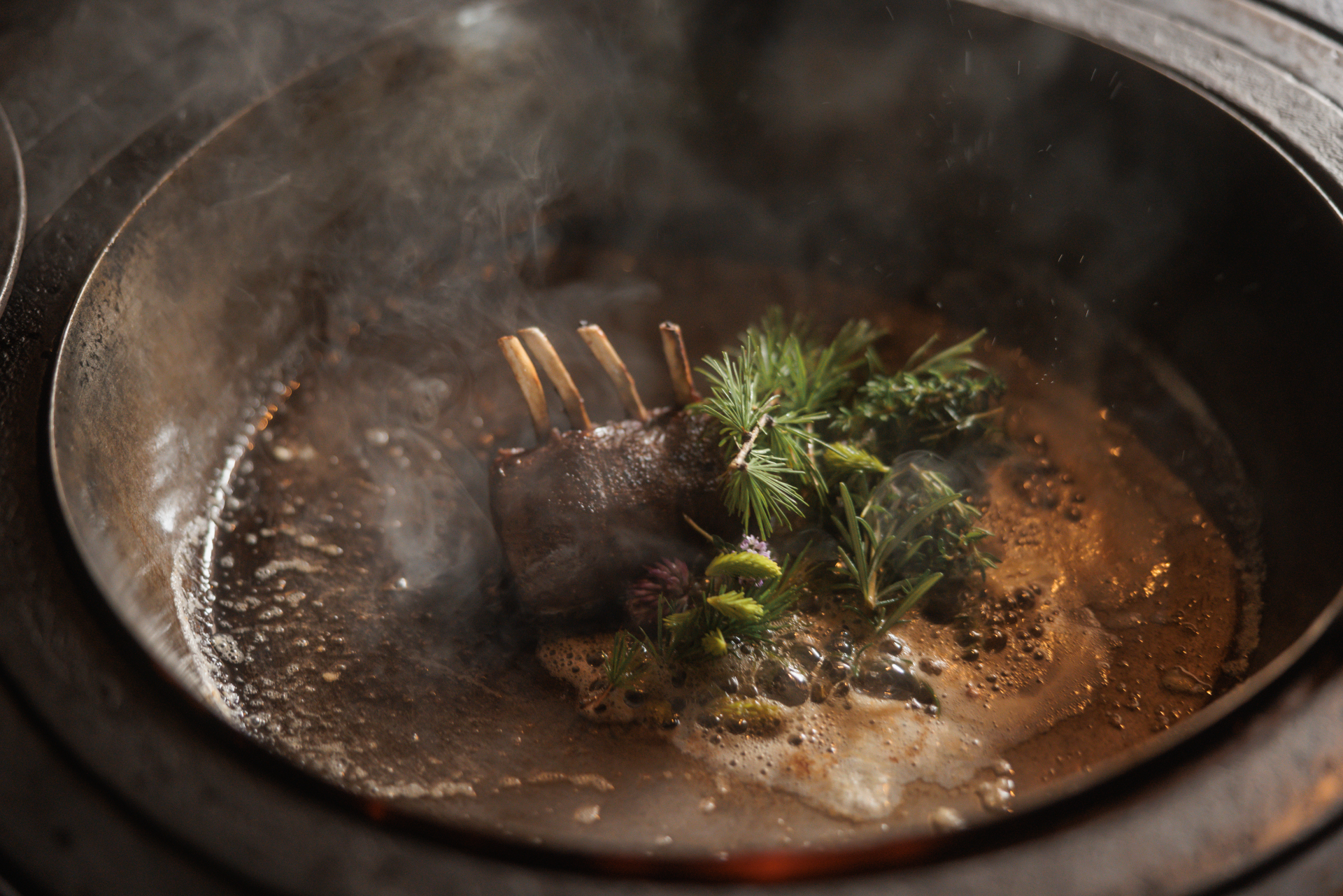 Mit Butter, Kräutern und Knoblauch erhält der Rehrücken seinen letzten Schiff. In der rund 600 Jahre alten Rauchkuchl wird in großen gusseisernen Pfannen über dem Feuer gekocht. ©RBMH / Florian Voggeneder