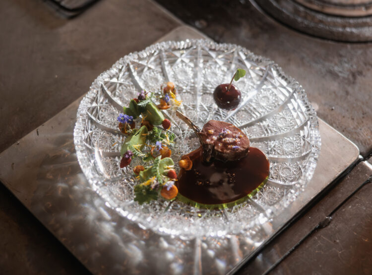 in Gedicht für alle Sinne. Der rosa gebratene Rehrücken wird mit Kräuterpüree, Wildkräuteröl, Fleischsauce, Eierschwammerln und der Pasteten-Kirsche angerichtet. ©Schwaigerlehen, Florian Voggeneder