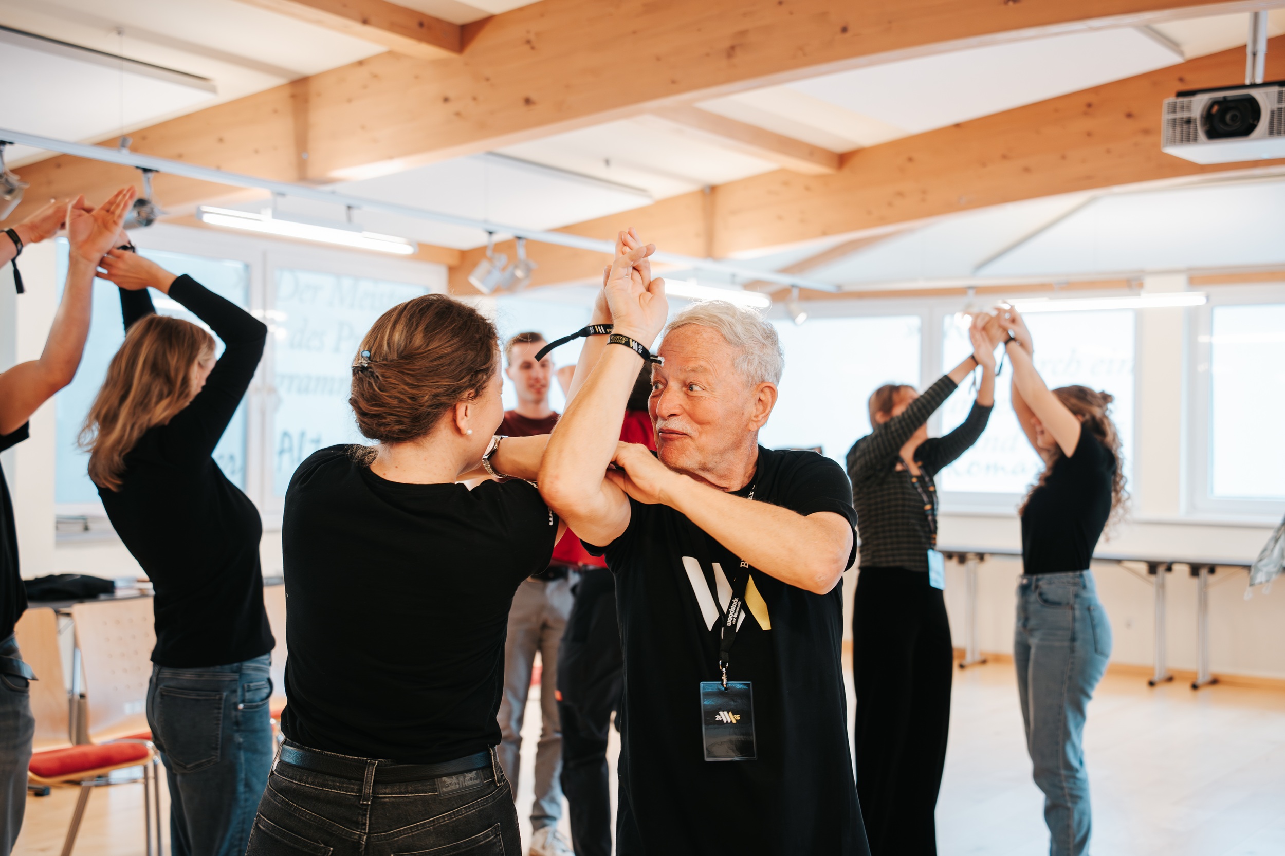 In einem hellen, ger&auml;umigen Raum mit gro&szlig;en Fenstern &uuml;ben die Teilnehmer an der Woodstock Academy Tanzschritte mit Partnern.