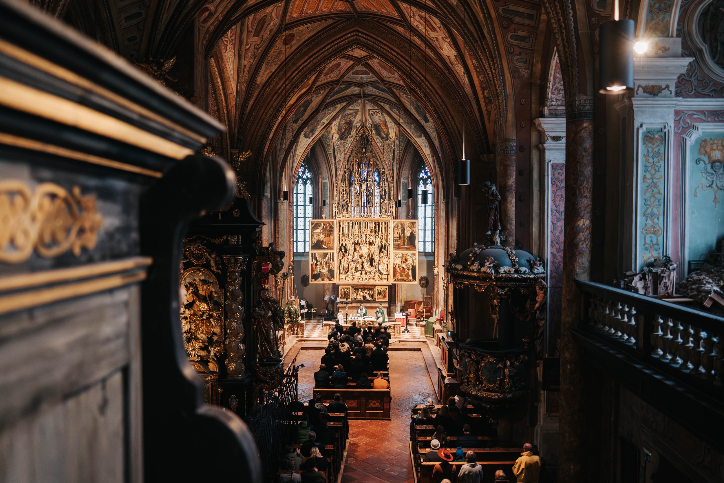Das Innere einer großen, reich verzierten Kathedrale der Woodstock Academy mit sitzenden Menschen vor einem kunstvollen Altar.