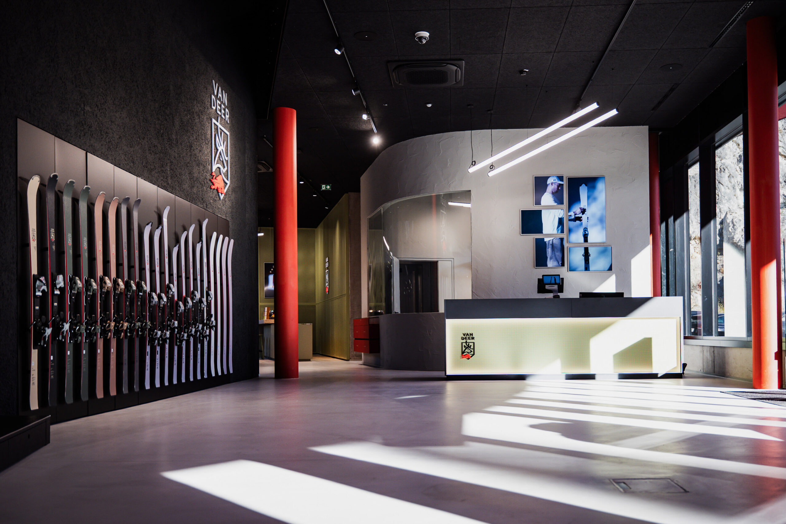 Modernes Skigeschäft mit ausgestellten Skiern, einem Empfangstresen und Sonnenlicht, das durch große Fenster einfällt.