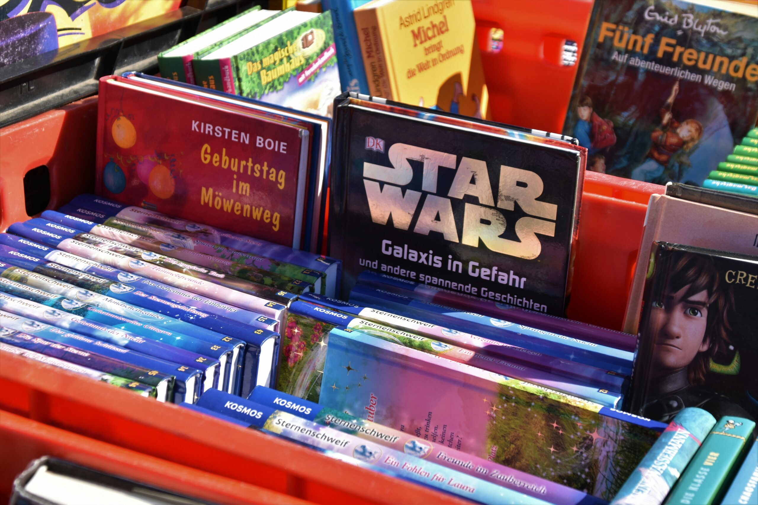 Bunte Kinderbücher, darunter Star Wars, aufrecht in einer roten Kiste auf der Flohmärkte in Salzburg.