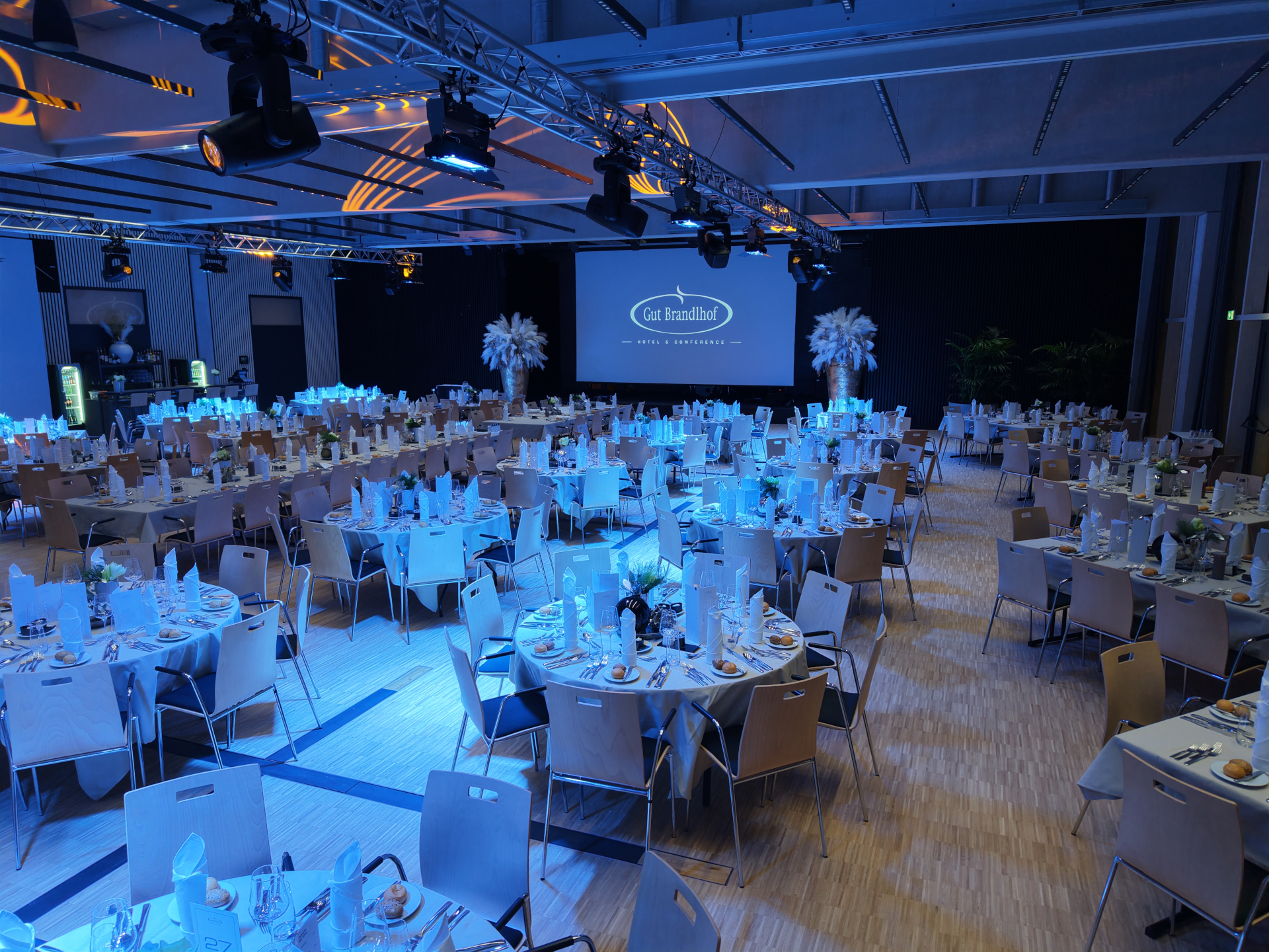 Gro&szlig;er Bankettsaal in bester Kongresslage, gedeckt mit runden Tischen und einer beleuchteten B&uuml;hne im Hintergrund.