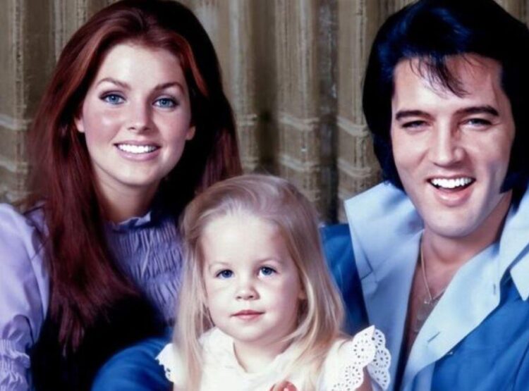 Ein lächelnder Mann und eine lächelnde Frau mit einem jungen Mädchen zwischen ihnen posieren für ein Porträt vor einem Vorhang.