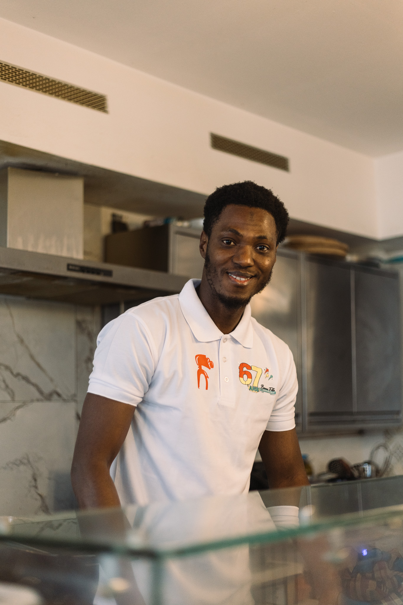 Ibrahim, der Besitzer des Le Nimba steht hinter einer Glastheke in seiner Küche.