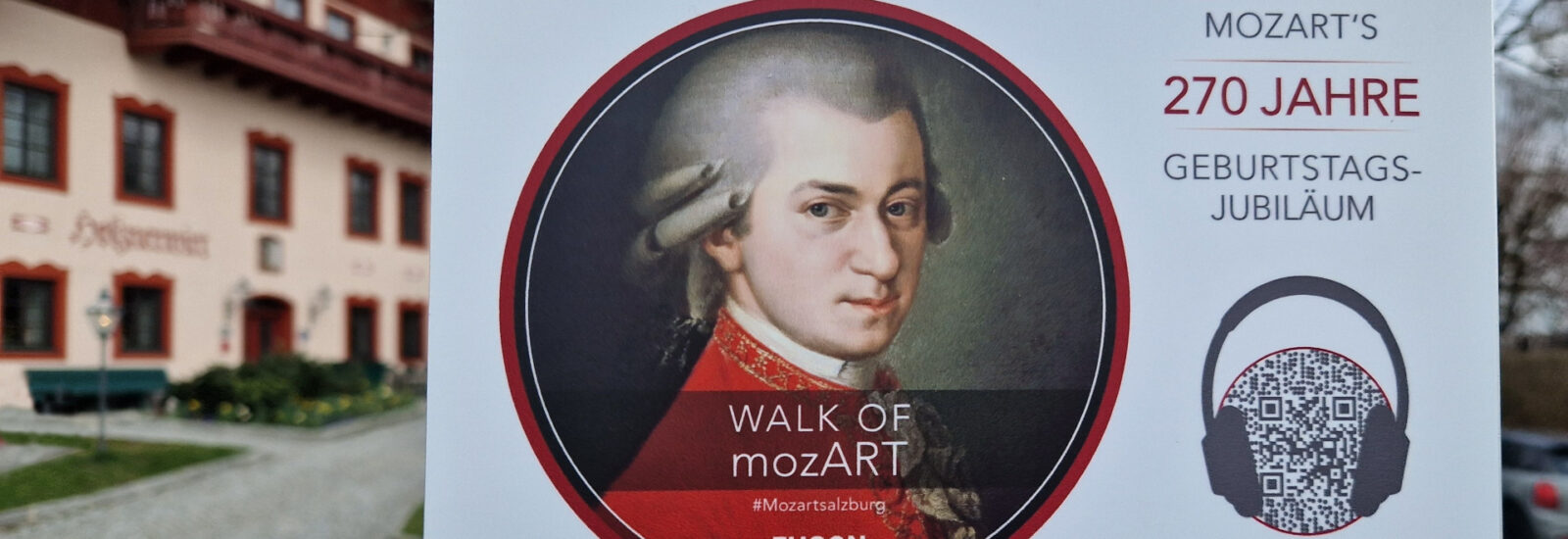 Plakat an einer Stange mit Mozarts Porträt, mit Text zu seinem 270. Geburtstag und einem QR-Code.