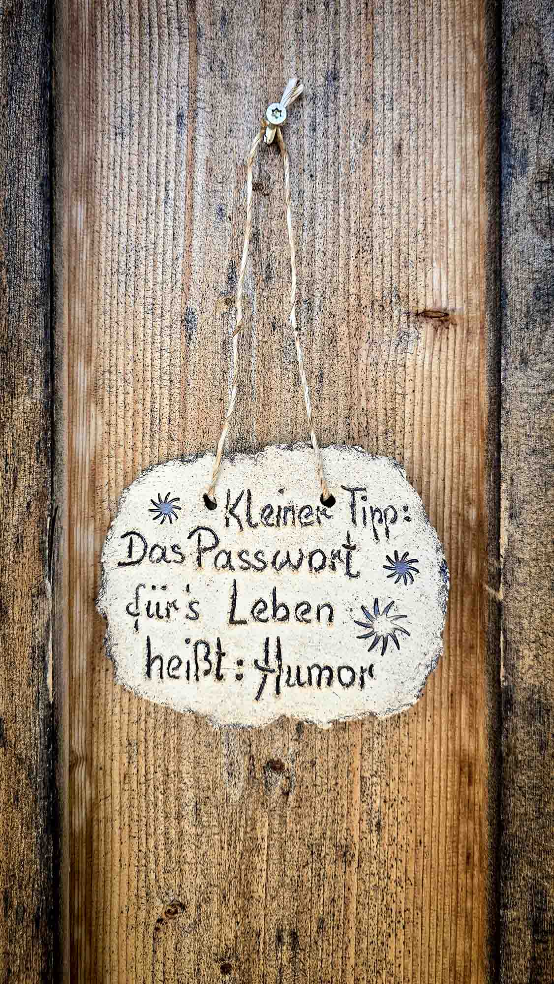 Auf einem Holzschild in Kathis Blumencaf&eacute; steht: Kleiner Tipp: Das Passwort f&uuml;rs Leben hei&szlig;t: Humor.