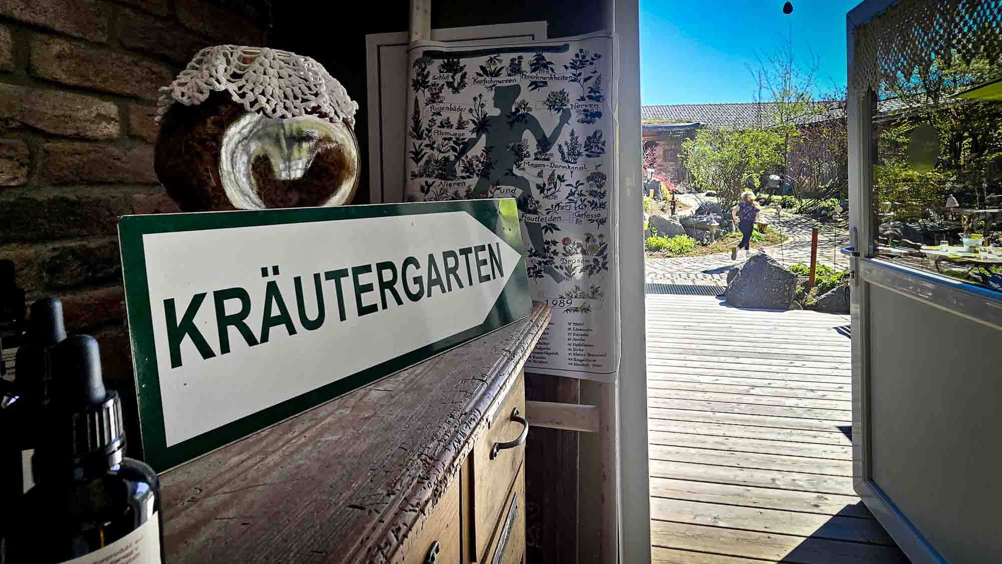 Ein Schild mit der Aufschrift KRÄUTERGARTEN in Kathis Blumencafé weist an einem sonnigen Tag auf einen Kräutergarten im Freien hin. © Melanie Deisl