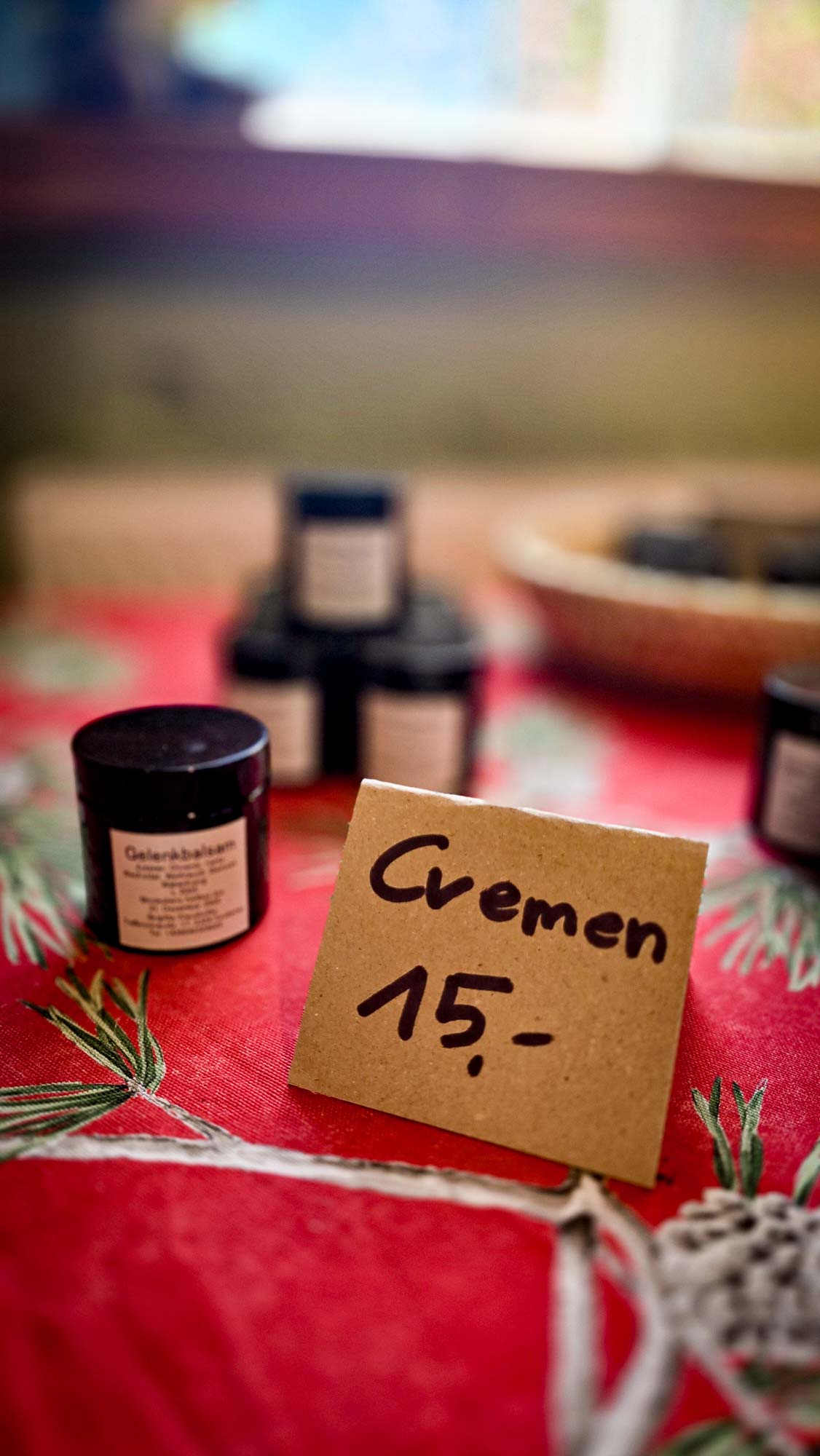 Kleine Gl&auml;ser mit der Aufschrift Cremen in Kathis Blumencaf&eacute;, die auf einer roten Tischdecke mit einem 15-Euro-Preisschild ausgestellt sind.