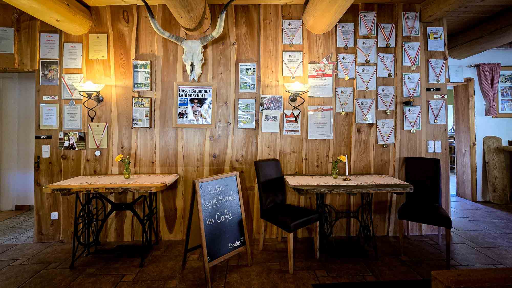 Im gemütlichen Kathis Blumencafé stehen zwei Holztische mit dunklen Stühlen unter Preisschildern.