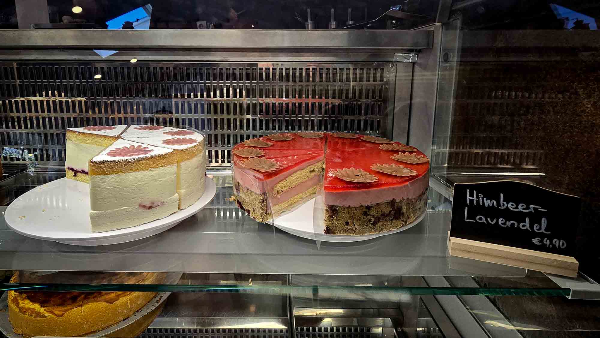Zwei Torten in der Vitrine von Kathis Blumencafé: eine weiße mit Sahne, eine rote Himbeer-Lavendel Torte  © Melanie Deisl