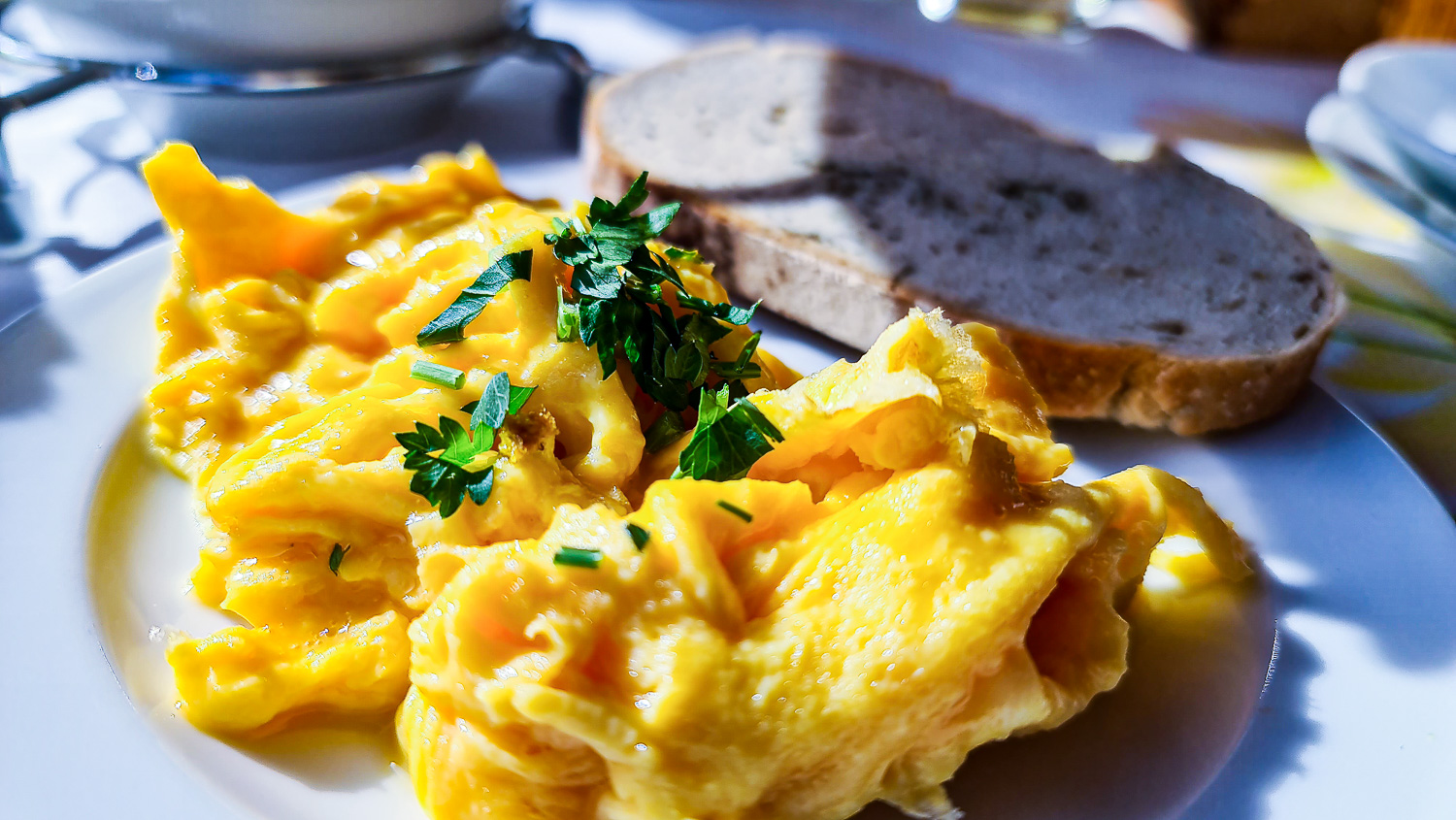 Rührei mit Kräutern, serviert mit zwei Scheiben Brot in Kathis Blumencafé. © Melanie Deisl