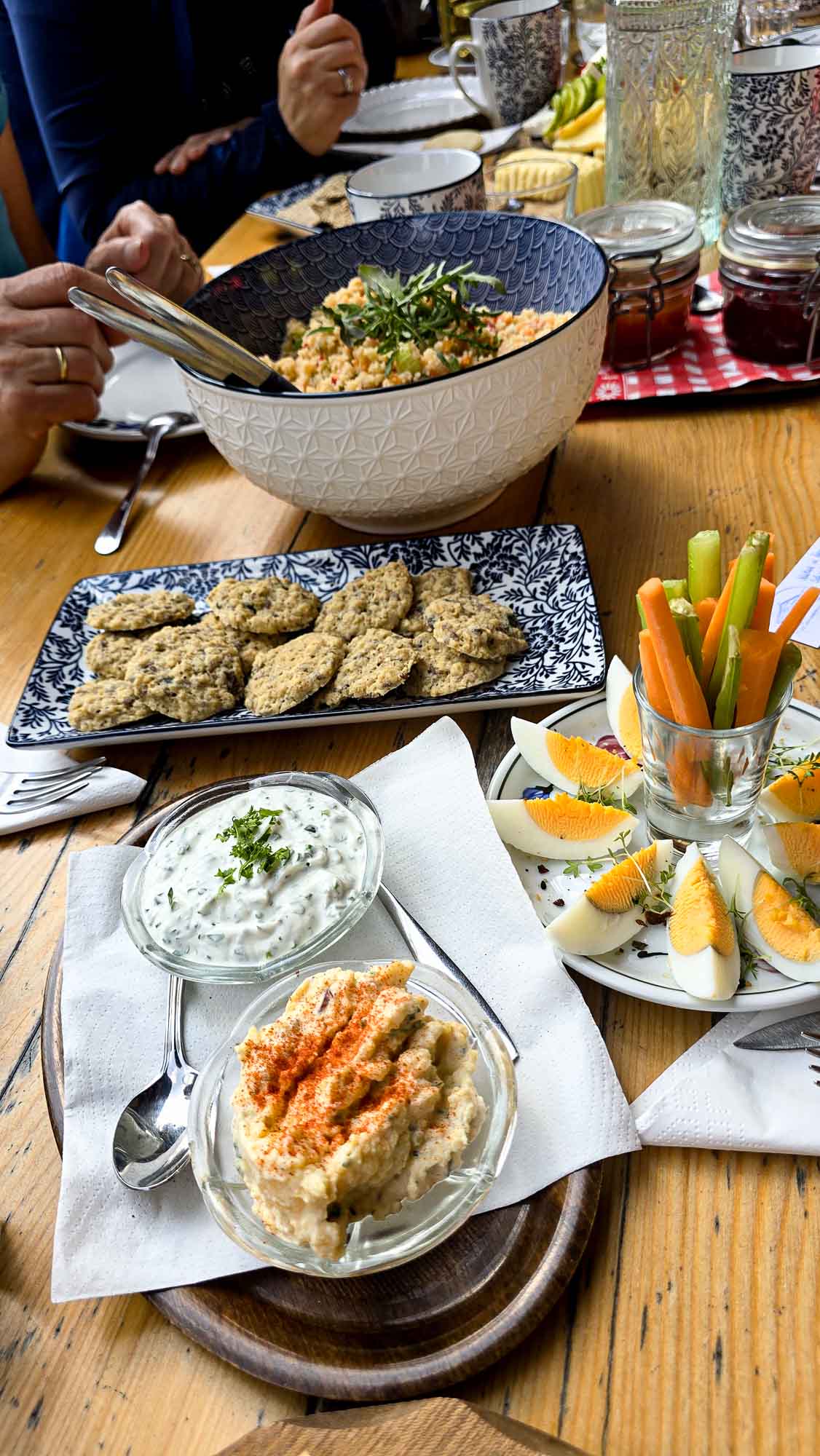 Ein Holztisch mit Dips, geschnittenen Eiern, Gem&uuml;sesticks und Crackern l&auml;dt zu einem gem&uuml;tlichen Beisammensein nach dem Yoga ein.