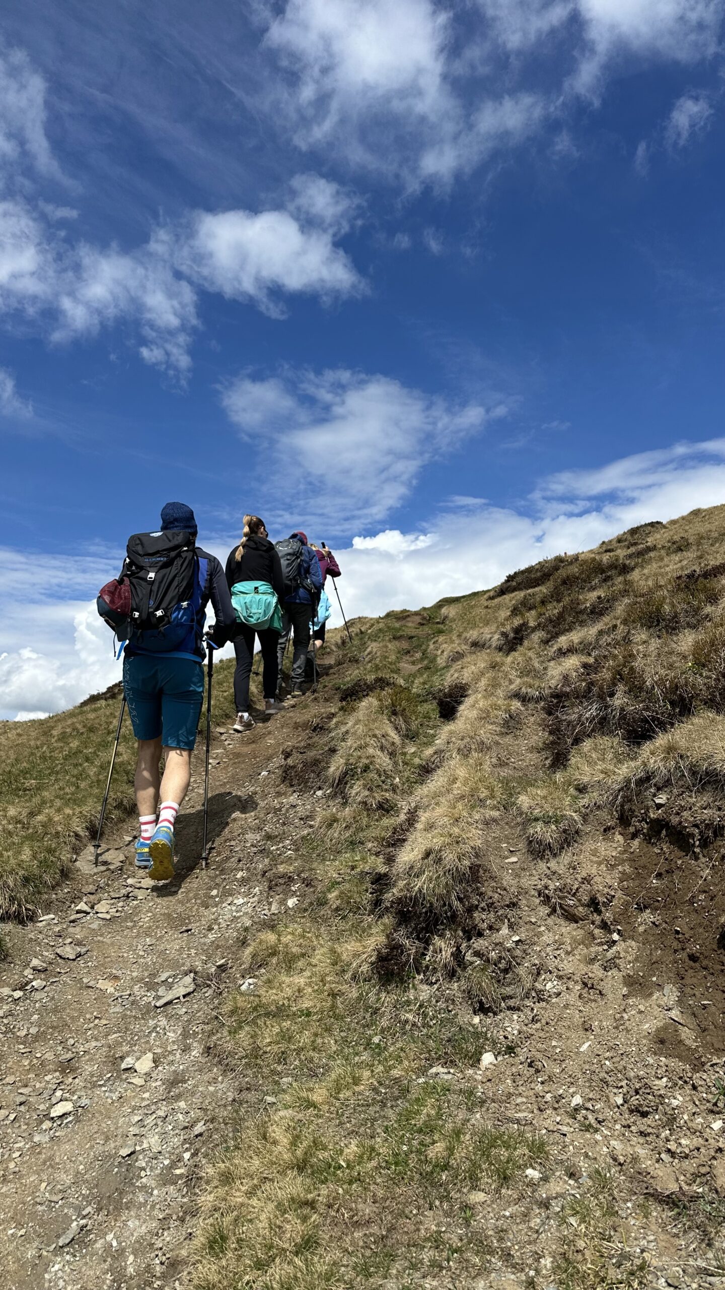 Eine Gruppe von Wanderern mit Rucks&auml;cken und Wanderst&ouml;cken steigt unter einem teilweise bew&ouml;lkten blauen Himmel die Schwalbenwand hinauf.