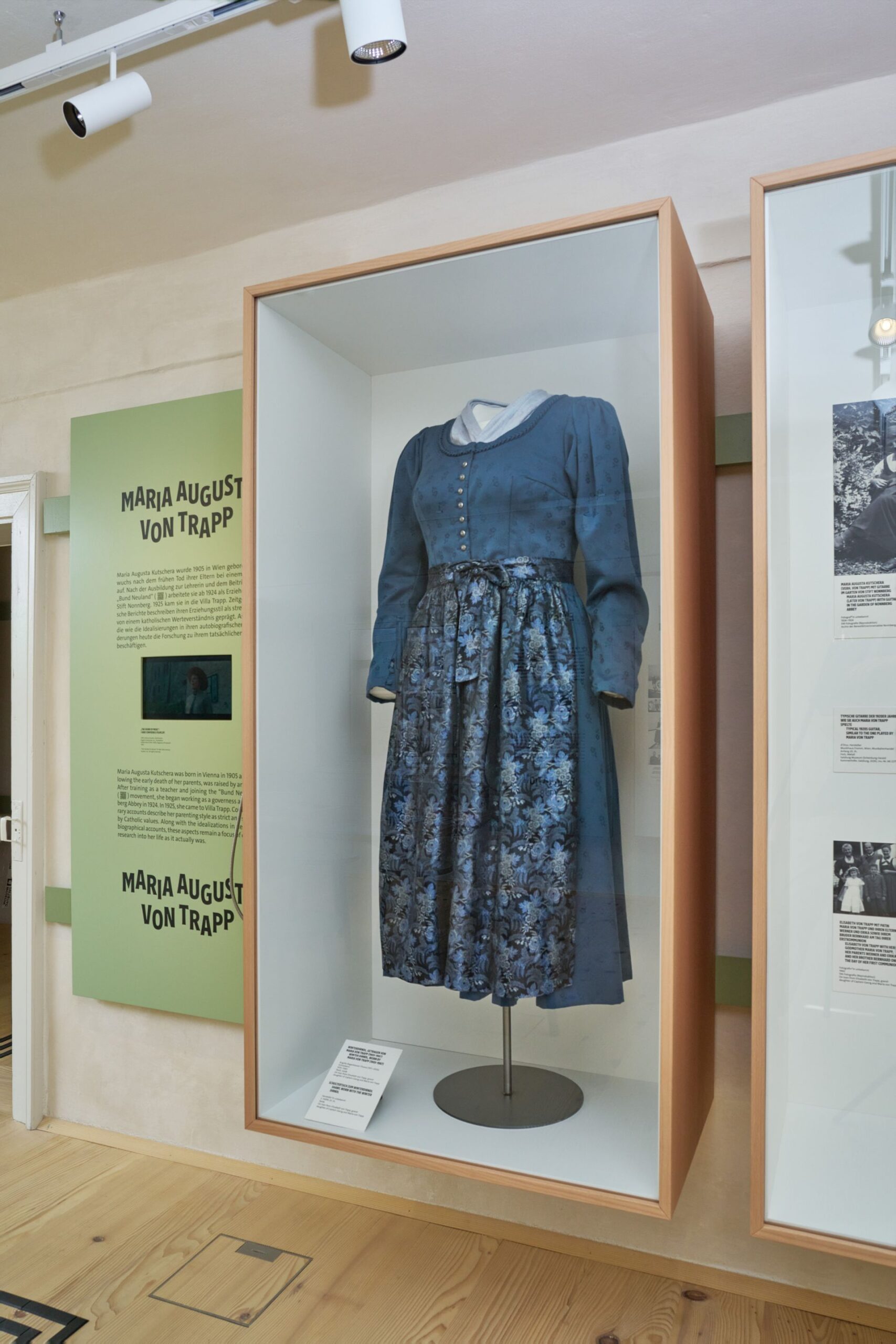 Ein blaues Kleid mit einem Rock mit Blumenmuster, ausgestellt in einer Glasvitrine im Rahmen einer Museumsausstellung &uuml;ber Maria von Trapp.