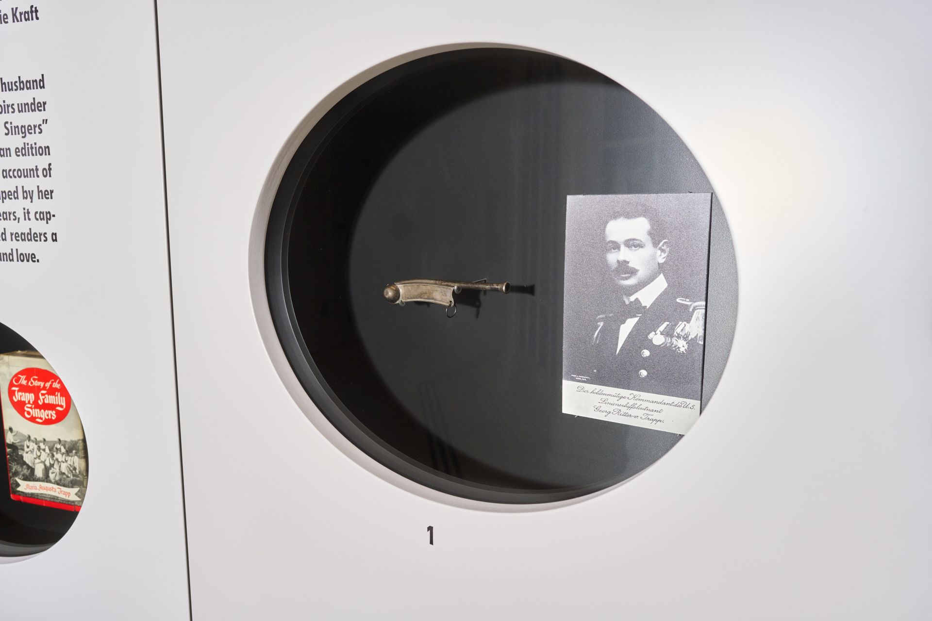 Ein kleines Klappmesser und ein Schwarz-Wei&szlig;-Portr&auml;t eines Mannes, ausgestellt in einer runden Museumsvitrine.