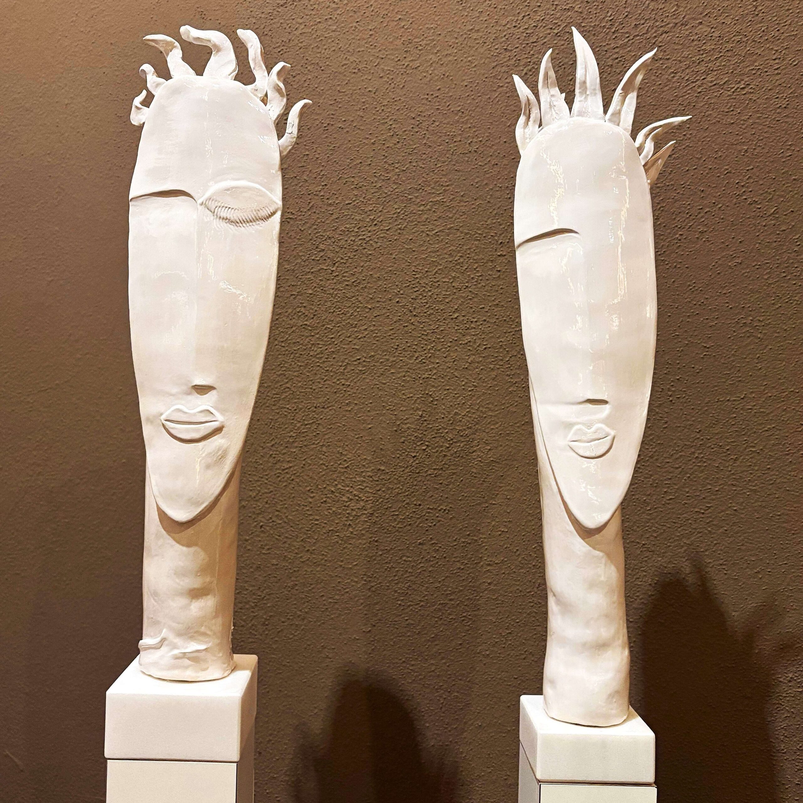 Zwei abstrakte weiße Skulpturen erinnern an das „Mountain-Art“-Projekt – mit langgestreckten Gesichtern auf quadratischen Sockeln.