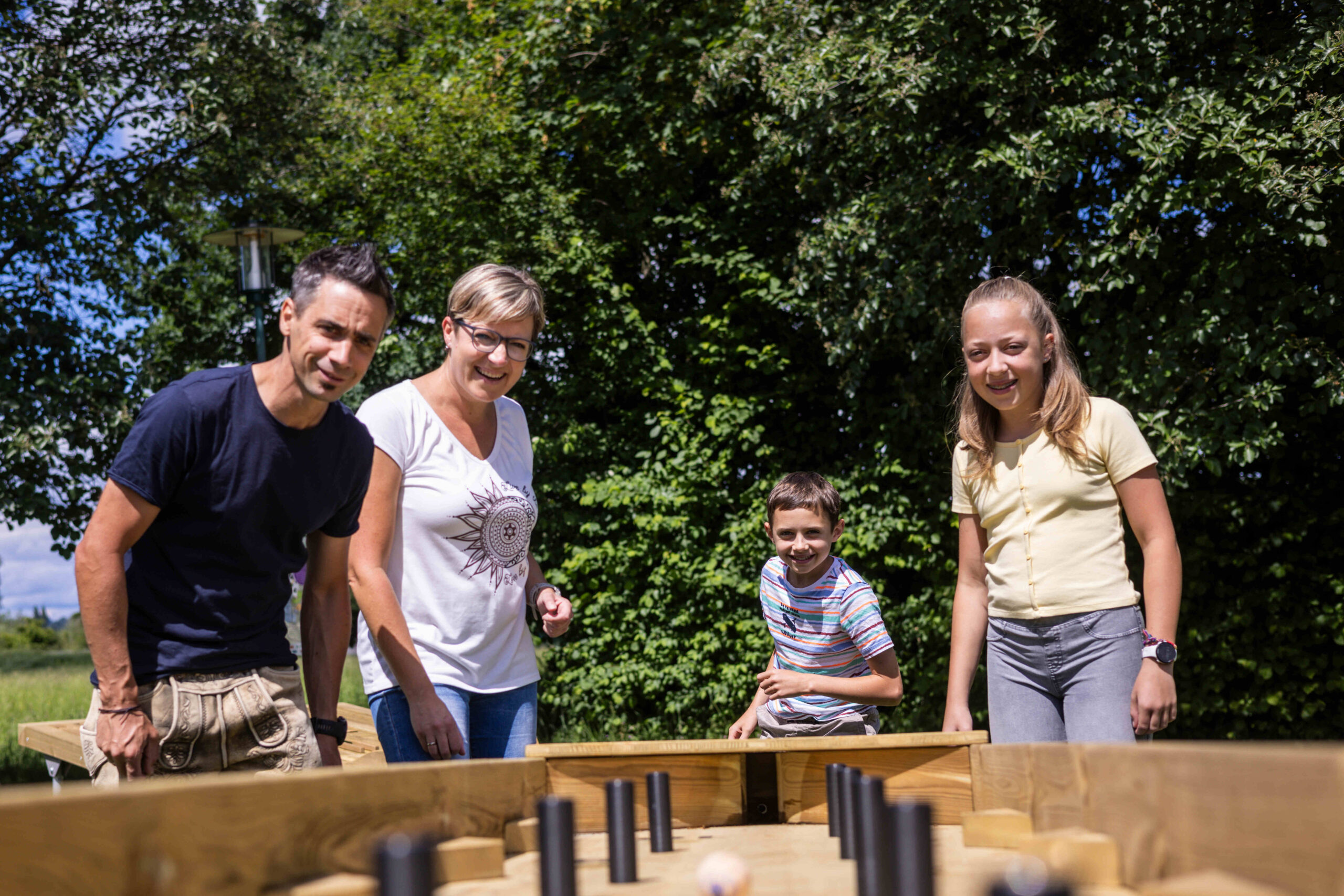 Vier Menschen lächeln und haben Spaß bei einem Brettspiel – das Salzburger Seenland hat acht neue Kugelbahnen als Attraktion.