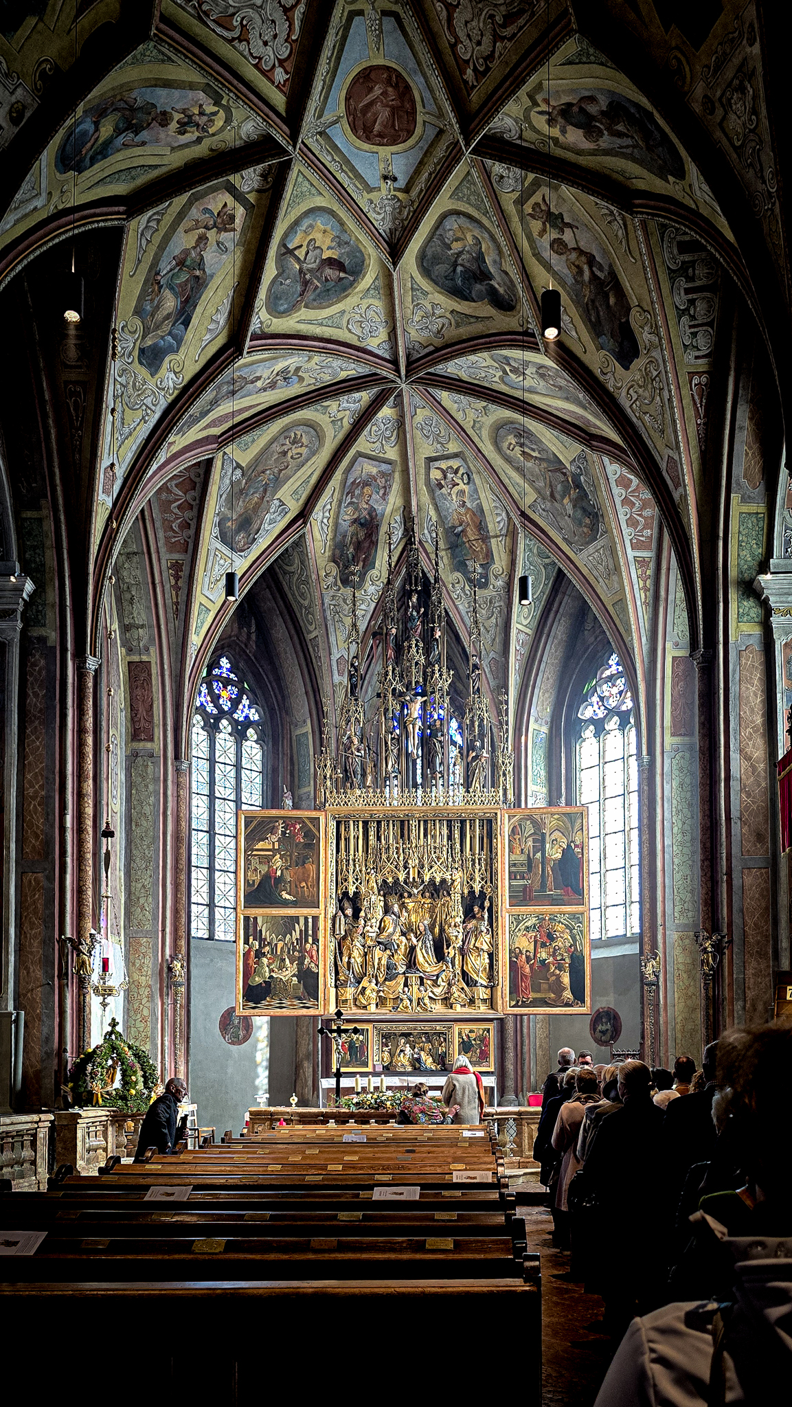 Pr&auml;chtiges Kircheninnere w&auml;hrend des Wolfgangi-Kirtags mit bemalter Decke, Buntglasfenstern und goldenem Altar.