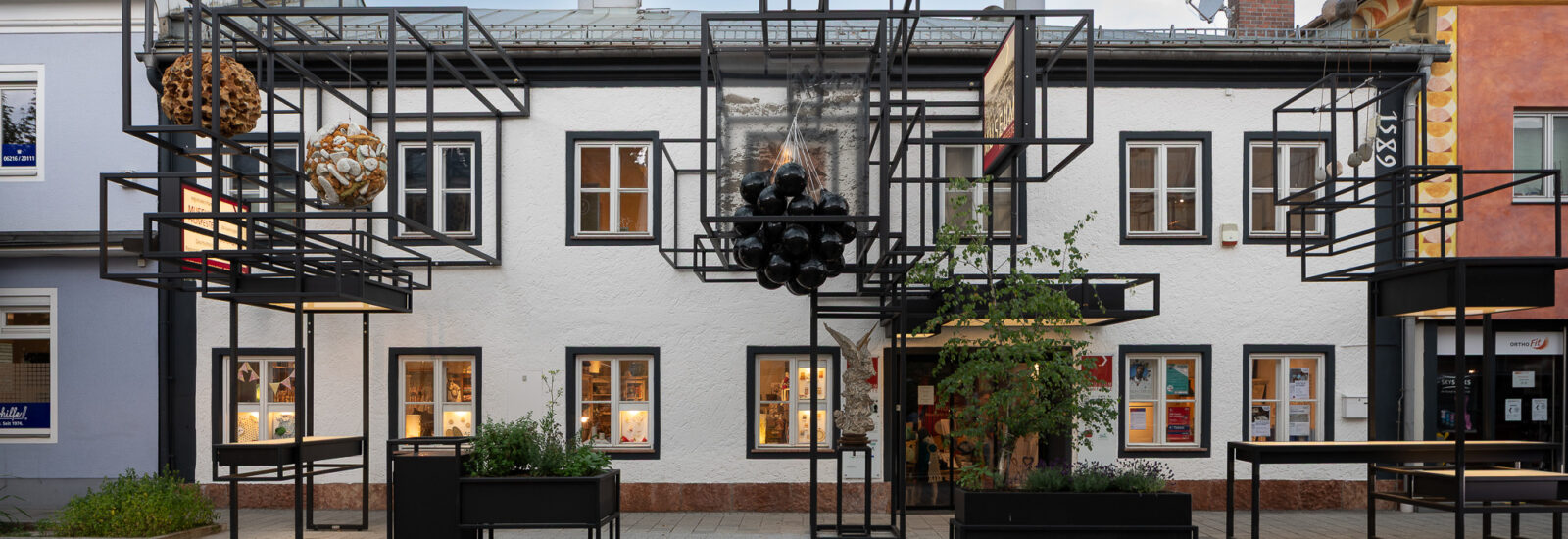 Das Museum Fronfeste befindet sich in einem weißen Gebäude mit schwarzer Stahlkonstruktion, skulpturalen Akzenten und Pflanzkübeln am Gehweg.