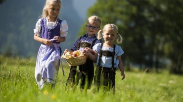 Drei Kinder spazieren über eine Wiese