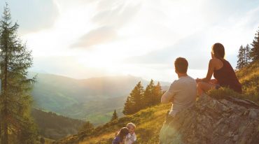 Familie genießt Sonnenuntergang auf der Alm